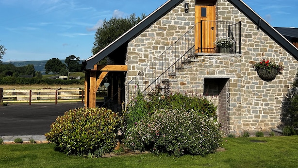 A stone building with a wooden door, a staircase, and a small balcony with a flower pot. - Studio-King Bed-Wye Valley Views (Bettws Newydd, Usk)