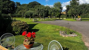 A park with a paved path, benches, and a metal table with a flower pot. - Studio-King Bed-Wye Valley Views (Bettws Newydd, Usk)
