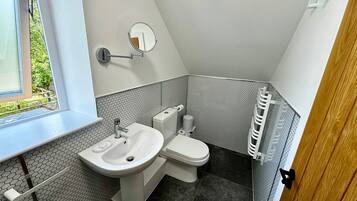Ein kleines Badezimmer mit Waschbecken, Toilette und Spiegel.