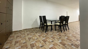 A dining area with a table and four chairs, a tiled floor, and a wall with a cabinet. - GL Hostal (Barranquilla)