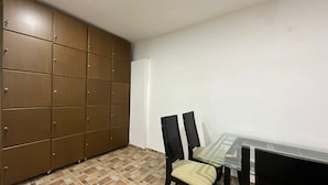 A room with a brown wardrobe, a glass table, and two chairs. - GL Hostal (Barranquilla)