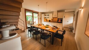 Une cuisine moderne avec une table à manger pour quatre personnes, un plancher en bois et un escalier menant à l’étage supérieur.