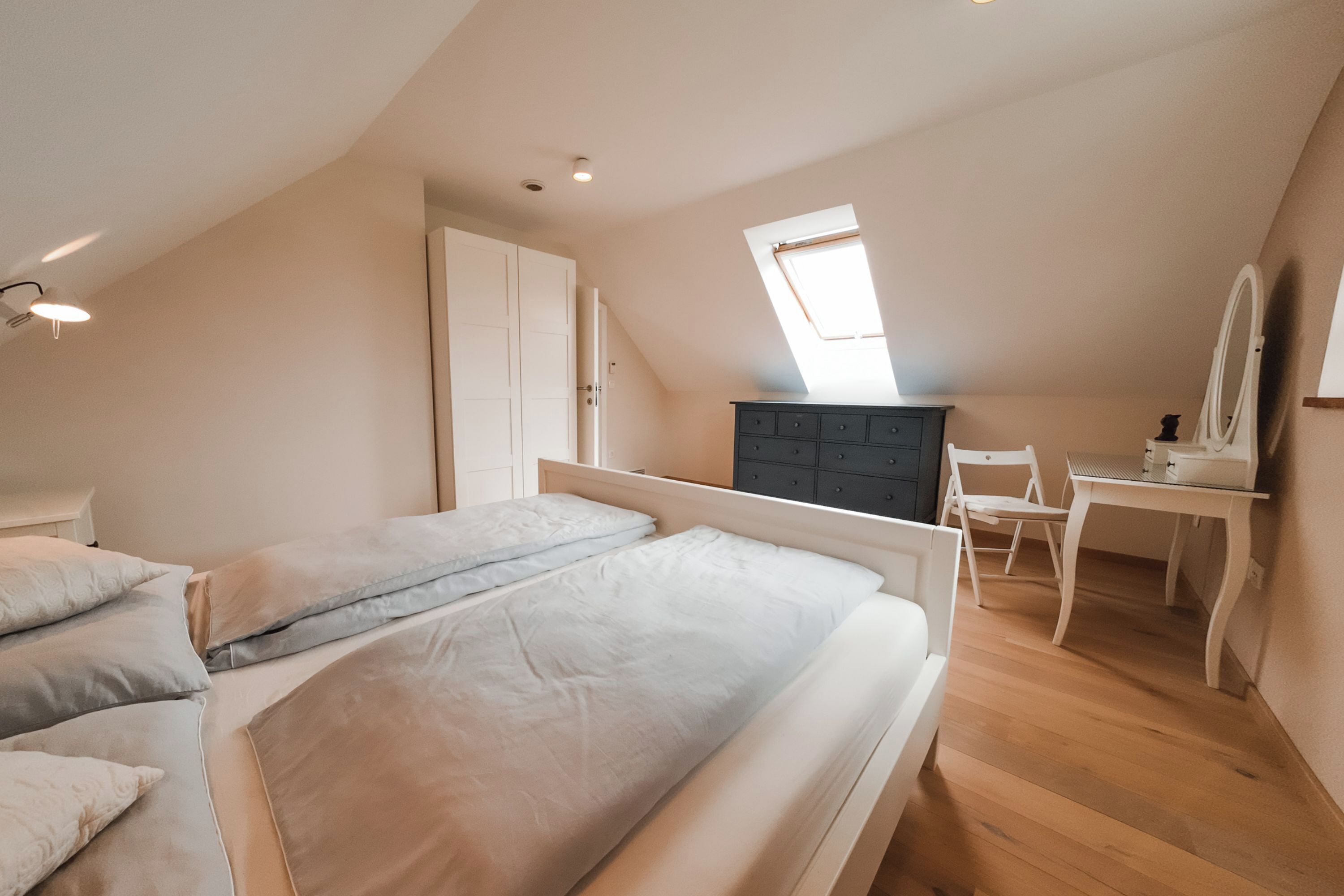 A bedroom with two beds, a desk, a chair, and a dresser.