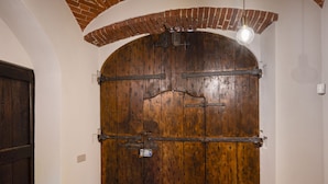 A large wooden door with metal reinforcements, a white wall, and a tiled floor. - Casa Calleri by Interhome (Briaglia)