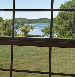 A view through a window with a grid pattern, a lake, and trees in the background.
