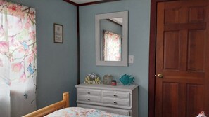 Une chambre à coucher avec un lit, une commode, un miroir et une porte.