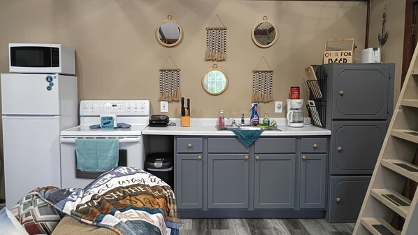 A compact kitchen with a microwave, stove, sink, and cabinets.