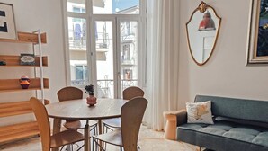 Een eetgedeelte met een ronde tafel, stoelen, een vaas en een bank.