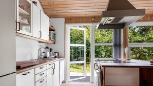 Een moderne keuken met witte kastjes, houten aanrechtbladen en een groot raam met uitzicht op groen.