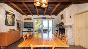 Un coin repas avec une table et des chaises en bois, un téléviseur et une cheminée.