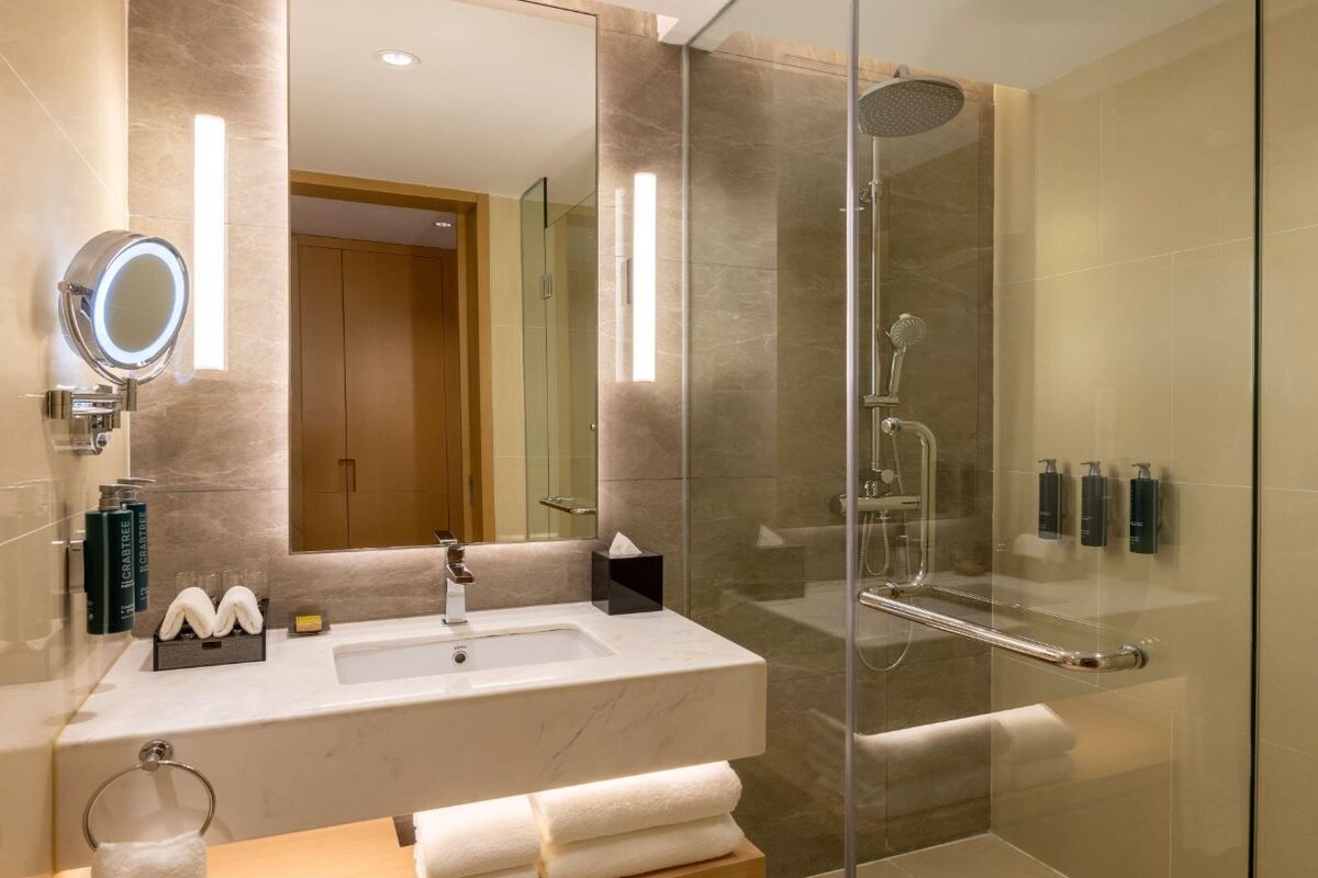 A modern bathroom with a glass shower enclosure, a vanity with a mirror, and a towel rack.