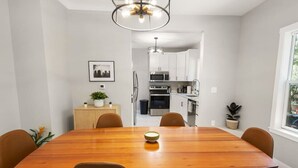 A dining area with a wooden table and six chairs, a potted plant, and a framed picture on the wall. - Mid-Century Connection | Nestled Amid Universities (Sioux Falls)