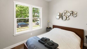 A bedroom with a bed, a window with a view of the outside, and a wall-mounted mirror arrangement. - Mid-Century Connection | Nestled Amid Universities (Sioux Falls)