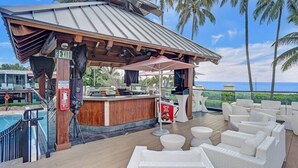 A beachside bar with white wicker furniture and a pool in the background. - Cozy Ocean View Condo / Beach Service & Pool /808 (Miami Beach)