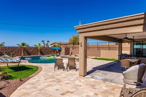 A backyard with a swimming pool, a covered patio area, and outdoor furniture. - Lake Havasu Oasis w/ Pool, Hot Tub, & Fun Games (Lake Havasu City)