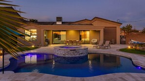 Ein modernes Haus mit Swimmingpool, Sitzgelegenheit im Freien und Whirlpool.