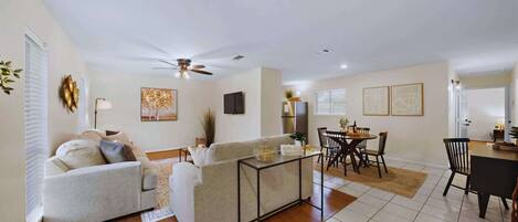 A modern living room with a sofa, coffee table, and dining area with chairs and a table.
