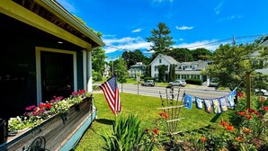 A residential street with houses, a parked car, and a flag. - High Street Haven, steps to Camden Harbor (Camden)