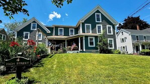 A two-story house with a front porch, a flag, and a street sign. - High Street Haven, steps to Camden Harbor (Camden)