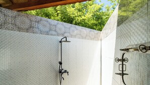 Zona de ducha con azulejos estampados y una puerta de metal.