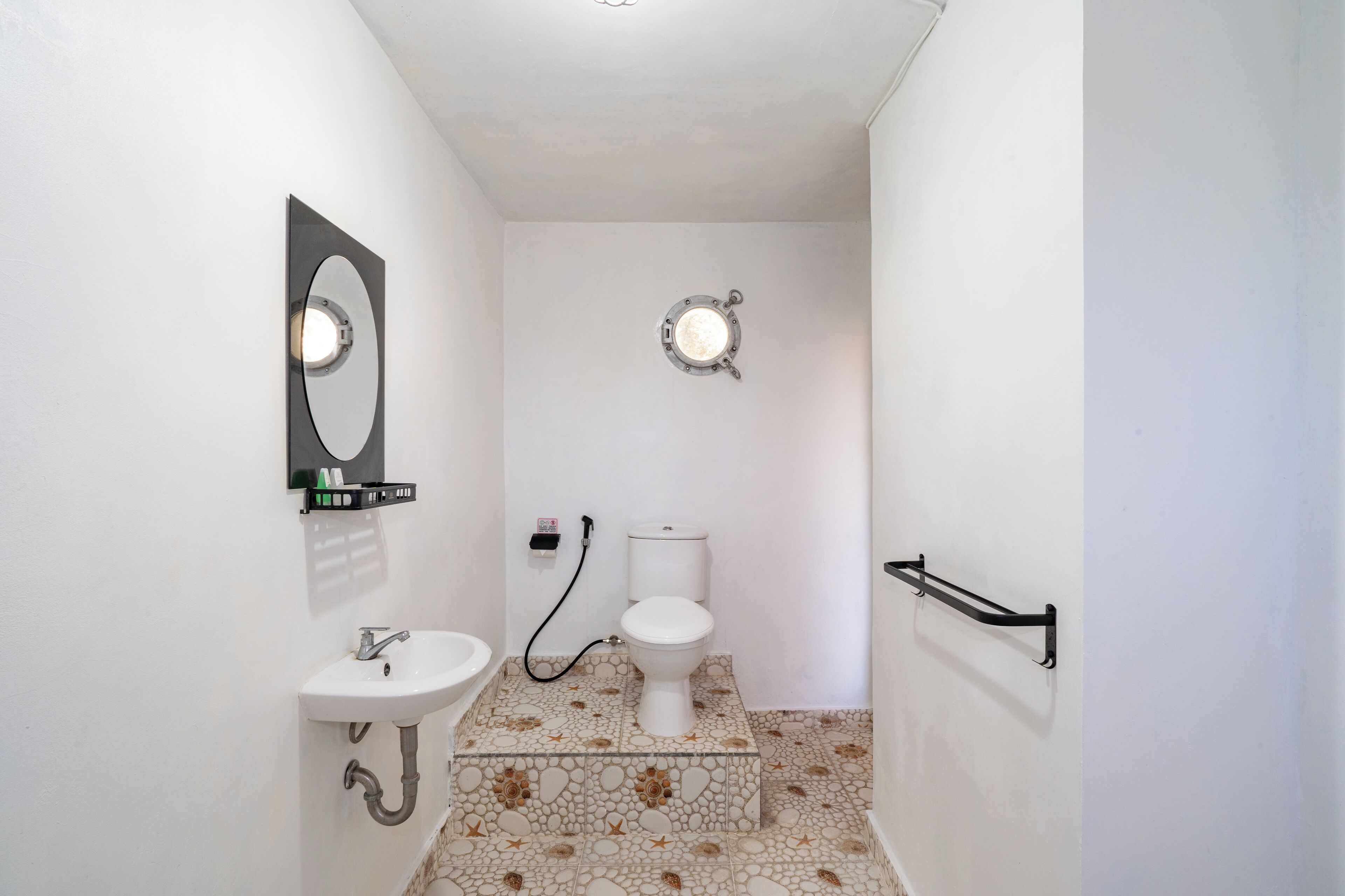 A bathroom with a white sink, toilet, and a mirror.
