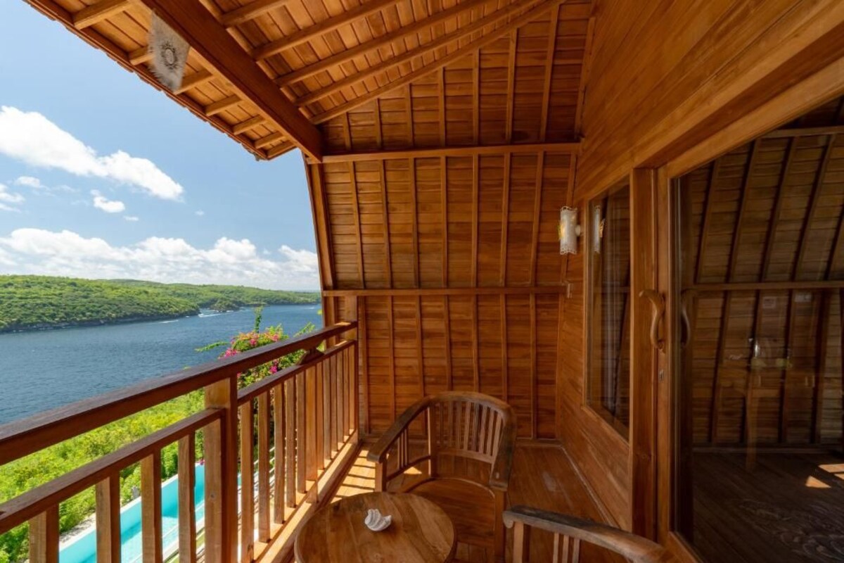 Un balcón de madera con vista a un lago y follaje.