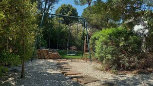 Un parque infantil con columpios, una escalera y piedras para pisar.
