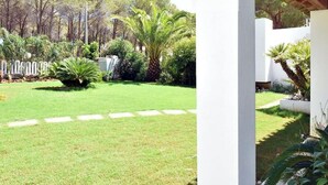 Un jardín bien cuidado con césped, palmeras y una cerca blanca.