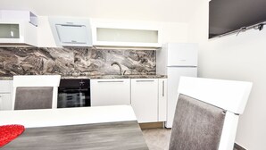 Eine moderne Küche mit weißen Schränken, einem eingebauten Backofen und einer Marmor-Spritzschutzwand.