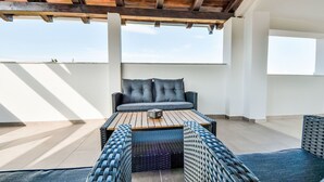 Eine Dachterrasse mit einer Couch, einem Couchtisch und Korbmöbeln.