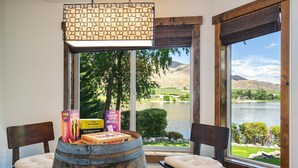 Una habitación con vistas a un lago, dos sillas, un barril de madera y juegos de mesa.