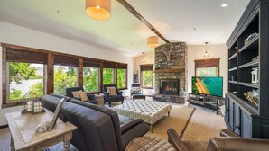 Un amplio salón con chimenea, mobiliario de cuero y ventanas grandes.