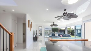 Una sala de estar moderna con una mesa de comedor de vidrio, un sofá y un ventilador de techo.
