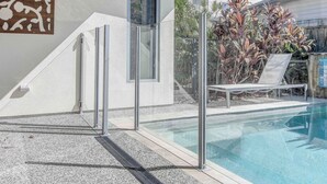 Un área moderna junto a la piscina, con vista despejada, una silla de descanso y un panel decorativo.