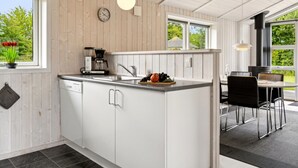 A modern kitchen with white cabinetry, a coffee maker, and a dining area with black chairs. - "Tayana" - 700m from the sea by Interhome (Sydals)
