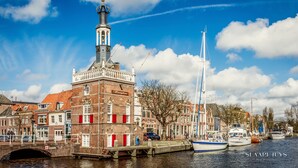 Un bâtiment historique doté d’une tour, un canal où naviguent des bateaux et un pont.