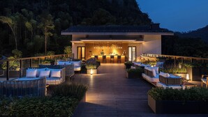A modern outdoor bar area with seating and a view of a forested hillside. - Garrya Xianju (Taizhou)