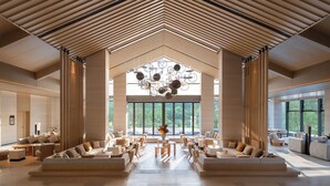 A spacious lobby with a high ceiling, modern furniture, and large windows offering views of greenery. - Garrya Xianju (Taizhou)