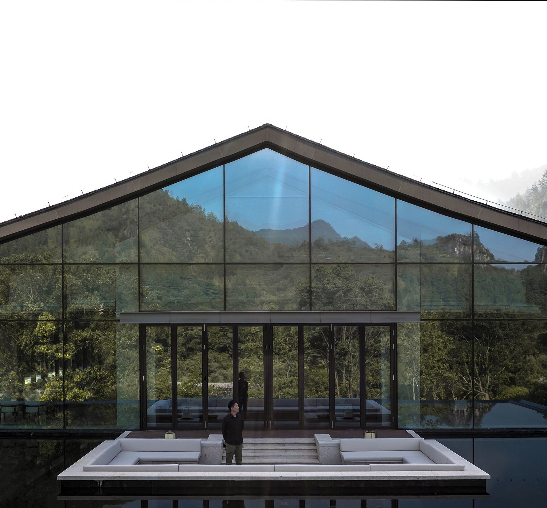 En moderne bygning med en stor glasfacade, der spejler et bjergrigt landskab.