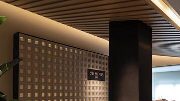 Zona de recepción con diseño moderno, que incluye un techo de madera, mostrador de recepción y una pared con diseño de cuadrícula.