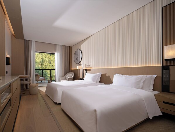 A hotel room with two beds, a desk, a chair, a large window with curtains, and a view of greenery outside. - Garrya Xianju (Taizhou)