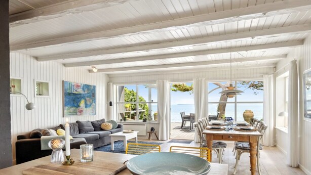 A spacious living area with a dining table, a sofa, and a view of the sea. - "Sten" - 30m from the sea by Interhome (Bjert)