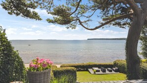 A wooden deck with a view of a calm lake, surrounded by greenery and a large tree. - "Sten" - 30m from the sea by Interhome (Bjert)