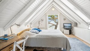 A high-ceilinged attic bedroom with a bed, desk, and TV. - "Sten" - 30m from the sea by Interhome (Bjert)