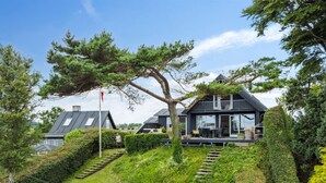 A modern house with a large tree in the front yard, a staircase leading up to the house, and a well-maintained garden. - "Sten" - 30m from the sea by Interhome (Bjert)