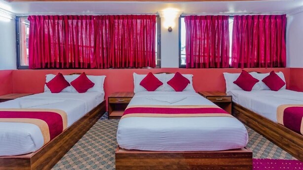 A hotel room with three beds, red curtains, and a patterned floor. - Hotel Aakansh (Sainbu)