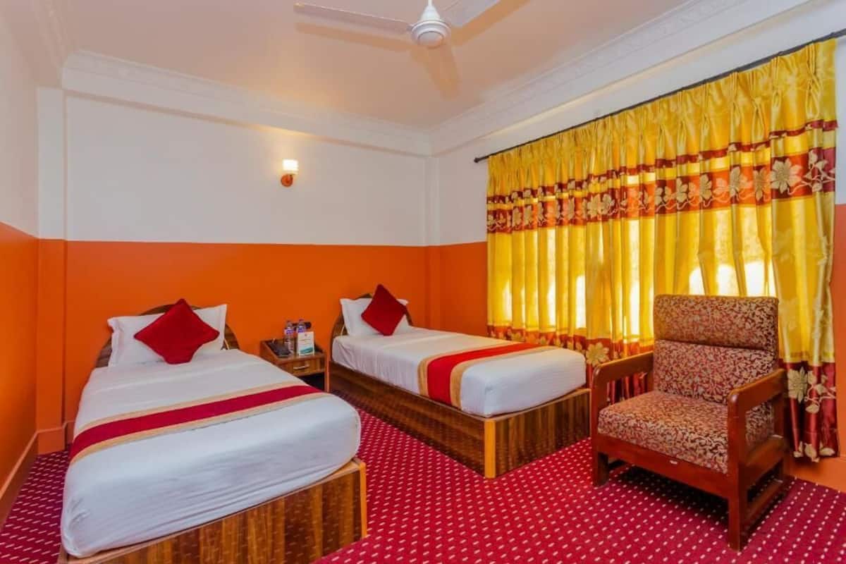 A hotel room with two beds, a chair, and a ceiling fan.