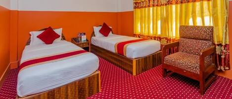 A hotel room with two beds, a chair, and a ceiling fan.