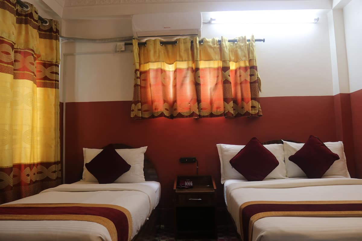A hotel room with two beds, a nightstand, a telephone, and a window with curtains.