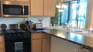A kitchen with a microwave, stove, and toaster. There are cabinets, a rug, and a trash can.